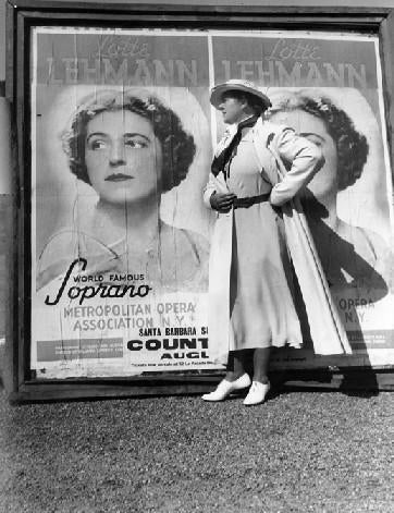 Lotte Lehmann stands next to a concert poster
