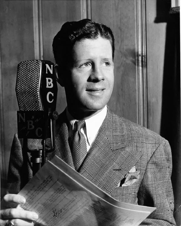 Rudy Vallee stands near an NBC microphone