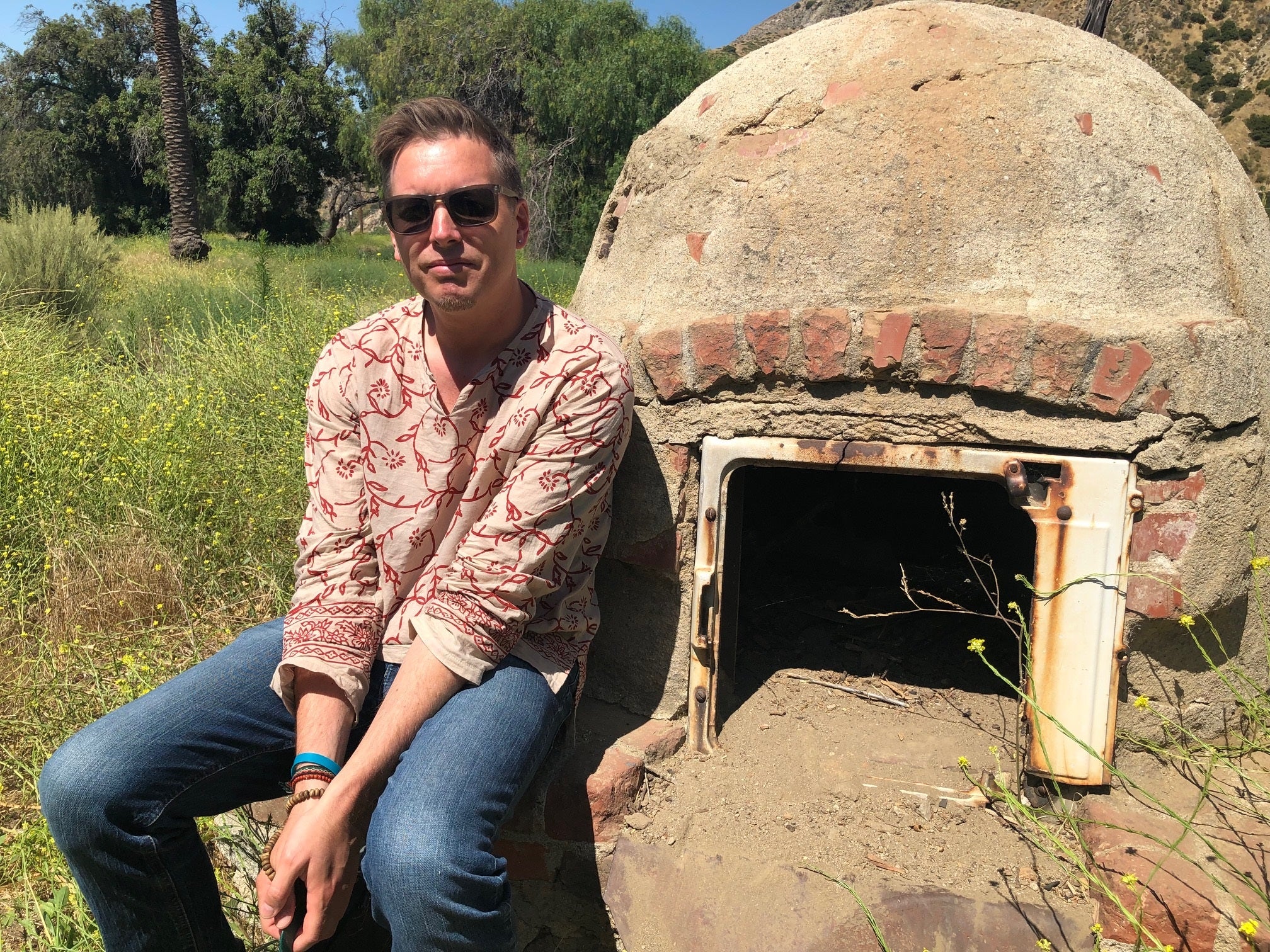 2020 Karmiole Research Fellow Brian Chidester sitting on a hearth outdoors.