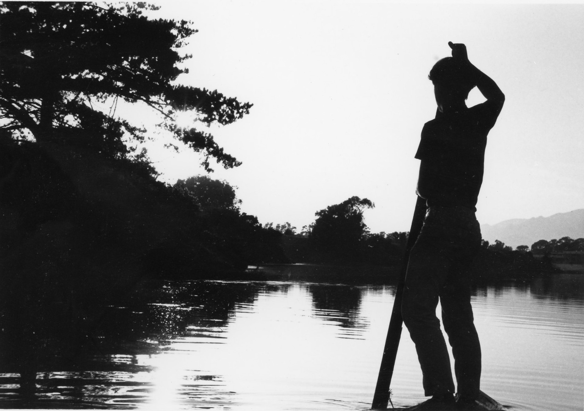 black and white photo of young man near lake