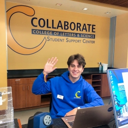 Student assistant waving at Collaborate Helpdesk in Library