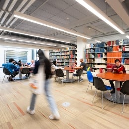 People sitting at tables and walking in the Sara Miller McCune Arts Library